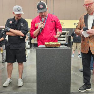 Ryan Ososky presents his Pizza Maker of the Year Championship winning pizza to the judges at the International Pizza Challenge during Pizza Expo in Las Vegas.