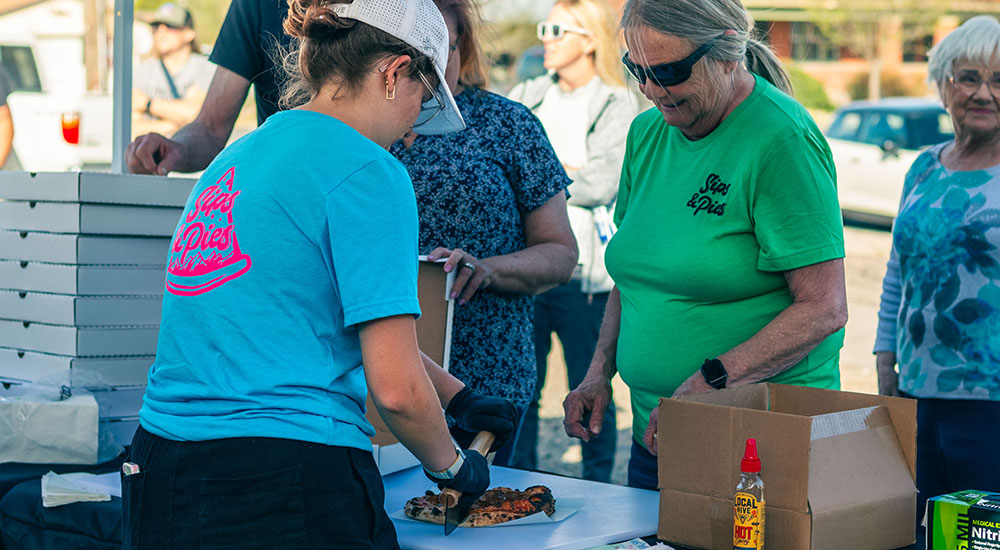 Image of woman cutting pizza during a mobile food truck pop-up event.