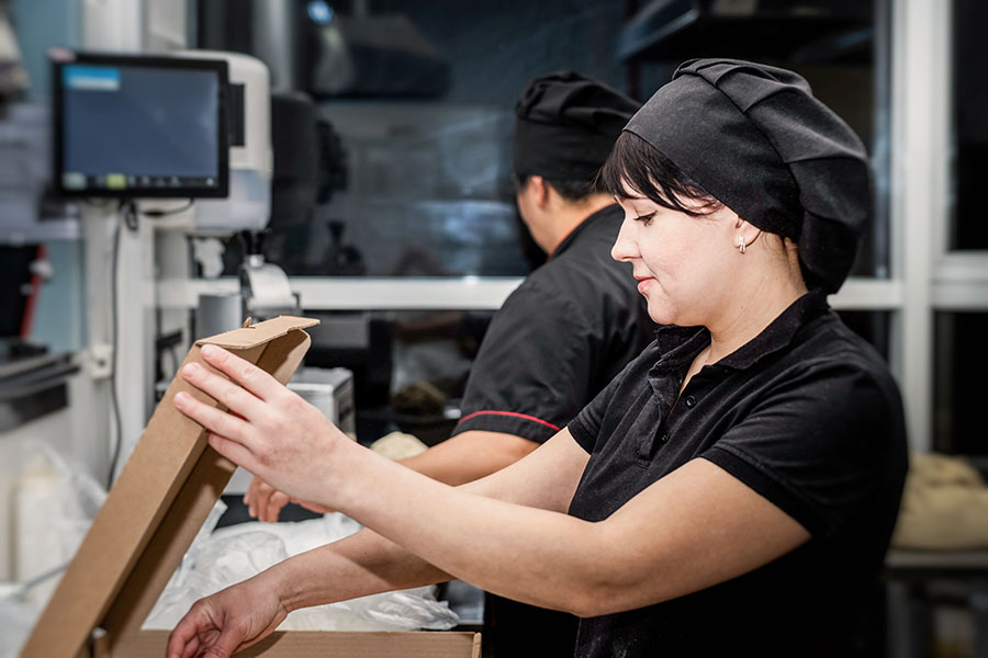 women at the pizzeria kitchen work on orders