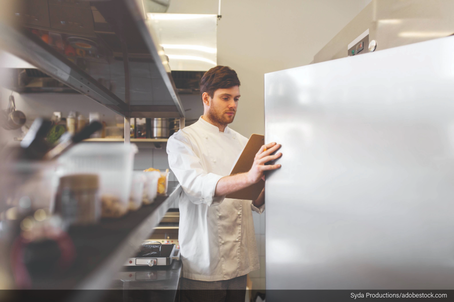 Image of restaurant chef looking in the industrial refrigerator.