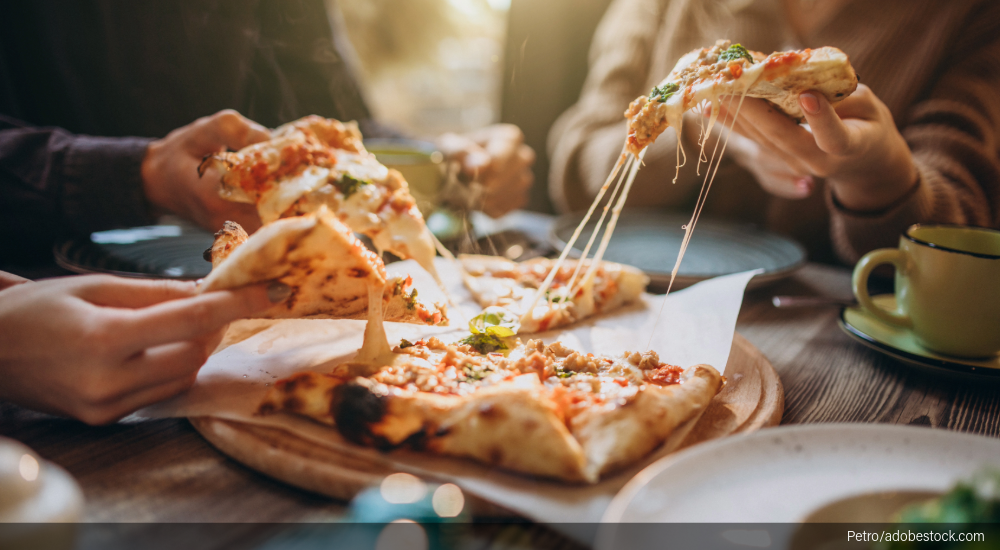Image of cheese pull as diners share a pizza.